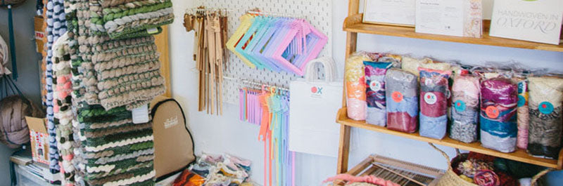 Studio wall featuring wall art and colourful looms, tools and yarn