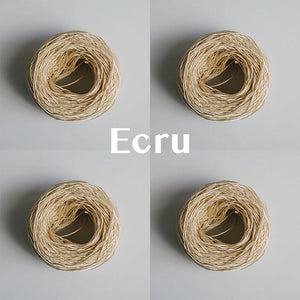 Four yarn cakes of 4-ply mercerised cotton yarn in ecru packaged in a compostable plastic bag and an Oxford Weaving Studio sticker