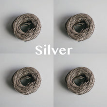 Load image into Gallery viewer, Four yarn cakes of 4-ply mercerised cotton yarn in silver packaged in a compostable plastic bag and an Oxford Weaving Studio sticker