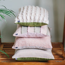 Load image into Gallery viewer, A pyramid stack of handwoven cushions by Cassandra Smith in a pleasing palette of cream, pink and green with a green plant nearby