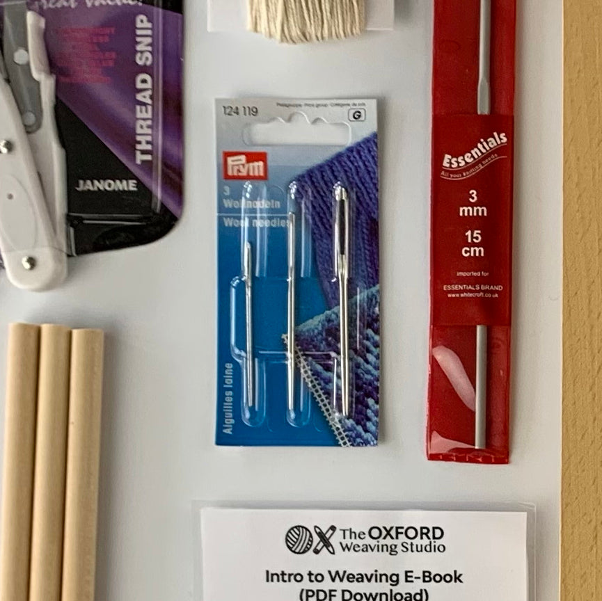 A package of Prym 3 tapestry needles of different sizes in original Prym packaging surrounded by other weaving accessories