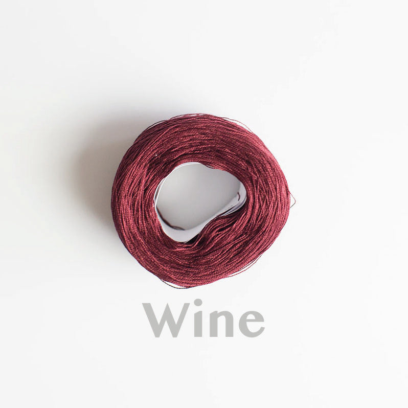 A 'wine' colour yarn cake of 2/16s mercerised cotton yarn