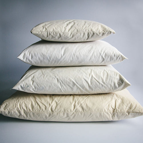 A pyramid stack of four different sized duck-filled cushion pads in cream