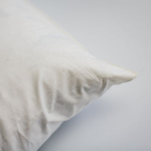 A close up of the corner of a duck-filled cushion pad covered in cotton cambray fabric.