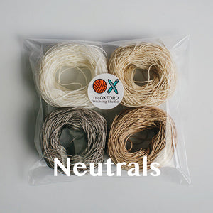Four yarn cakes of 4-ply mercerised cotton yarn in neutral colours packaged in a compostable plastic bag with an Oxford Weaving Studio sticker