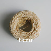 Load image into Gallery viewer, One yarn cake of 4-ply mercerised cotton yarn in ecru packaged in a compostable plastic bag and an Oxford Weaving Studio sticker