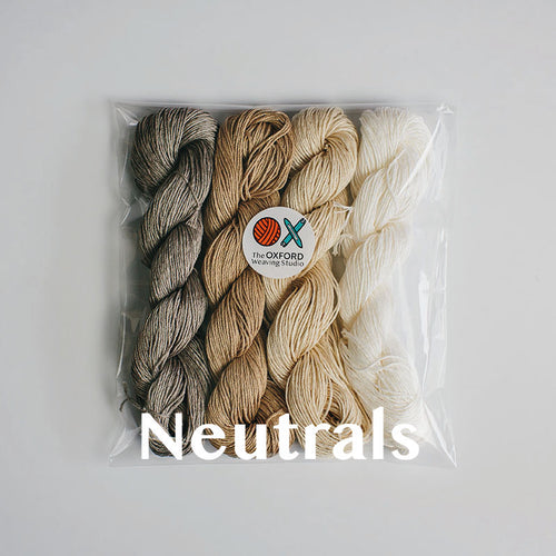 Four skeins of mercerised cotton yarn in neutral colours packaged in a compostable plastic bag and an Oxford Weaving Studio sticker