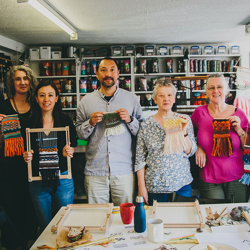 Group of people smiling and holding their finished wall-hangings from their Intro to Frame Loom Weaving workshop