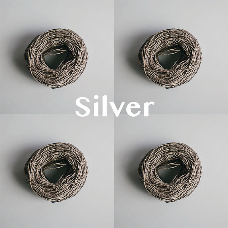 Four yarn cakes of 4-ply mercerised cotton yarn in silver packaged in a compostable plastic bag and an Oxford Weaving Studio sticker