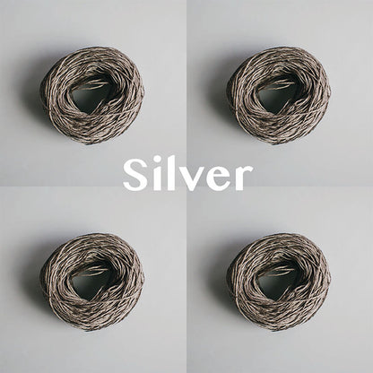 Four yarn cakes of 4-ply mercerised cotton yarn in silver packaged in a compostable plastic bag and an Oxford Weaving Studio sticker
