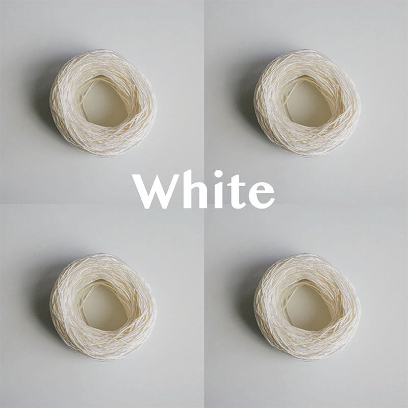 Four yarn cakes of 4-ply mercerised cotton yarn in white packaged in a compostable plastic bag and an Oxford Weaving Studio sticker